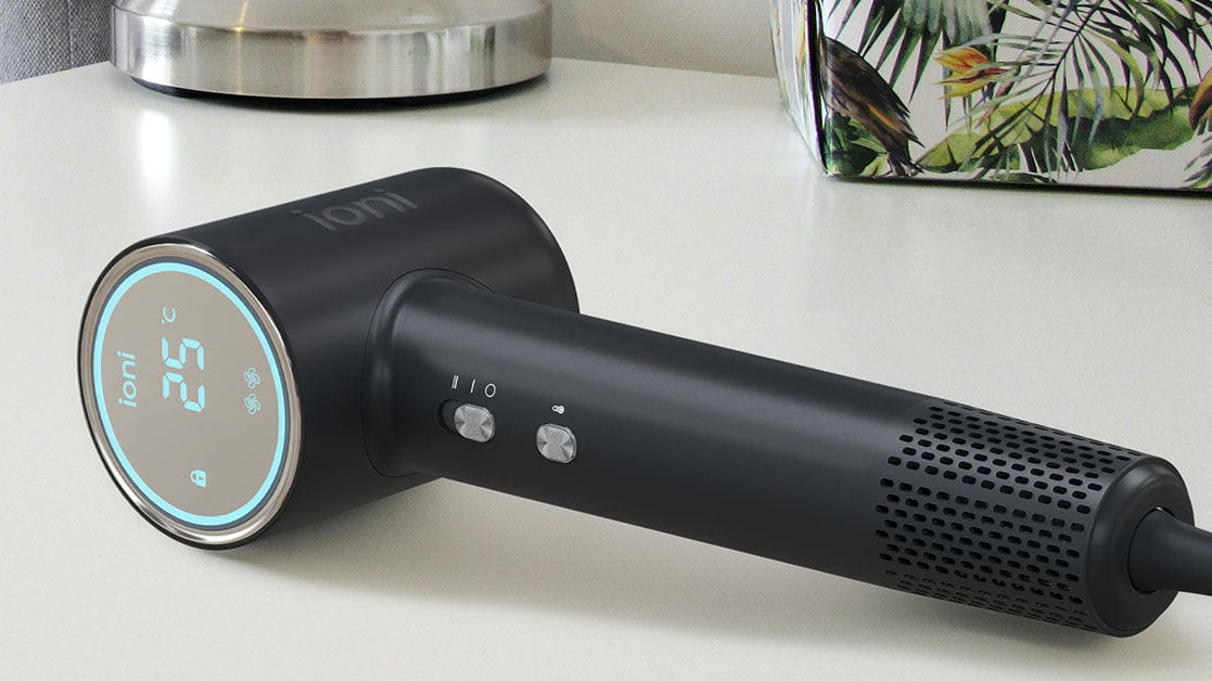 Black hair dryer with digital display on a white surface