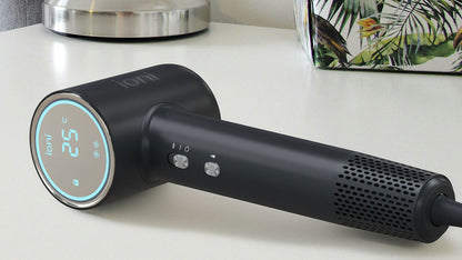 Black hair dryer with digital display on a white surface